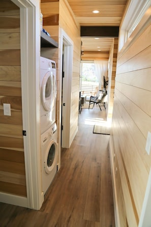 Un espace buanderie équipé d’un lave-linge et d’un sèche-linge, avec des murs en bois, et un coin repas comprenant des chaises et une table.