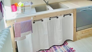 A compact kitchen with wooden cabinets, a skylight, a sink, and a colorful rug.