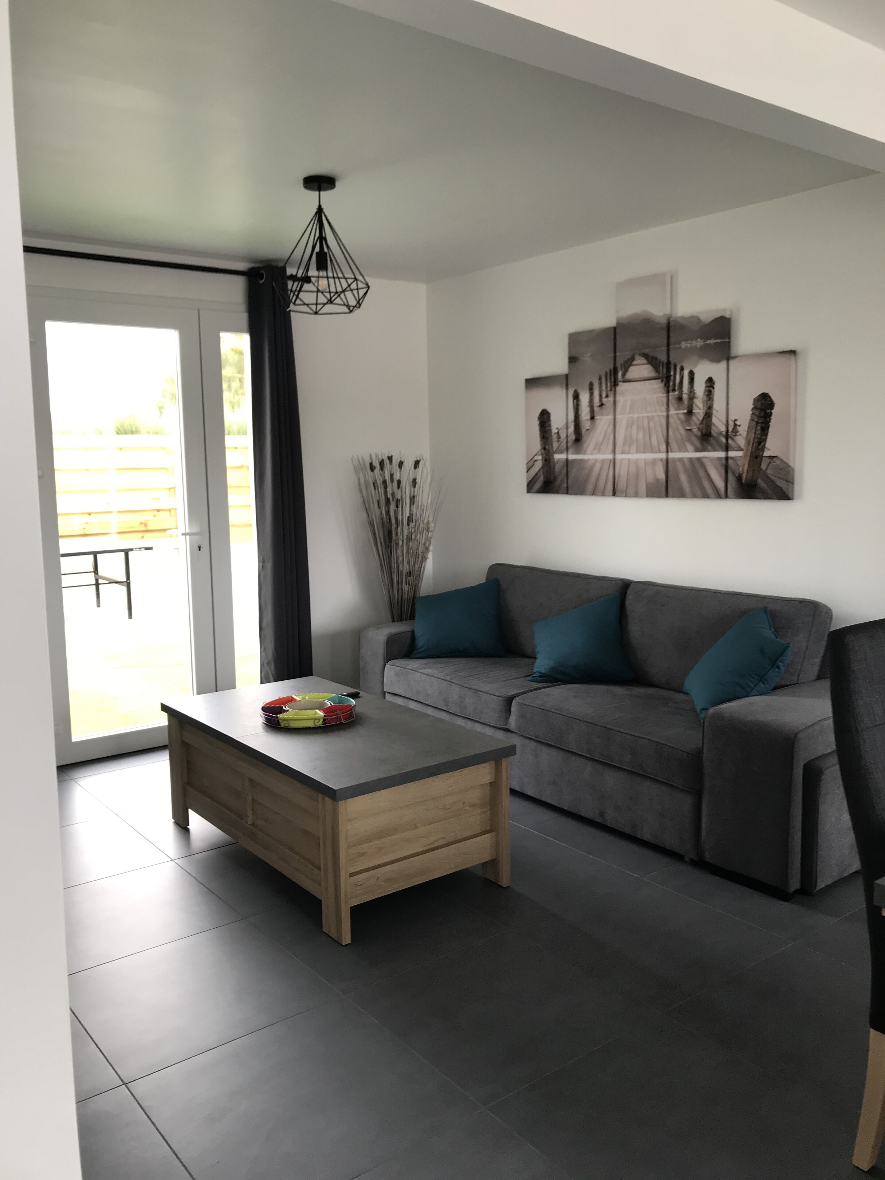 A modern living room with a grey sofa, a wooden coffee table, and a large abstract painting on the wall.