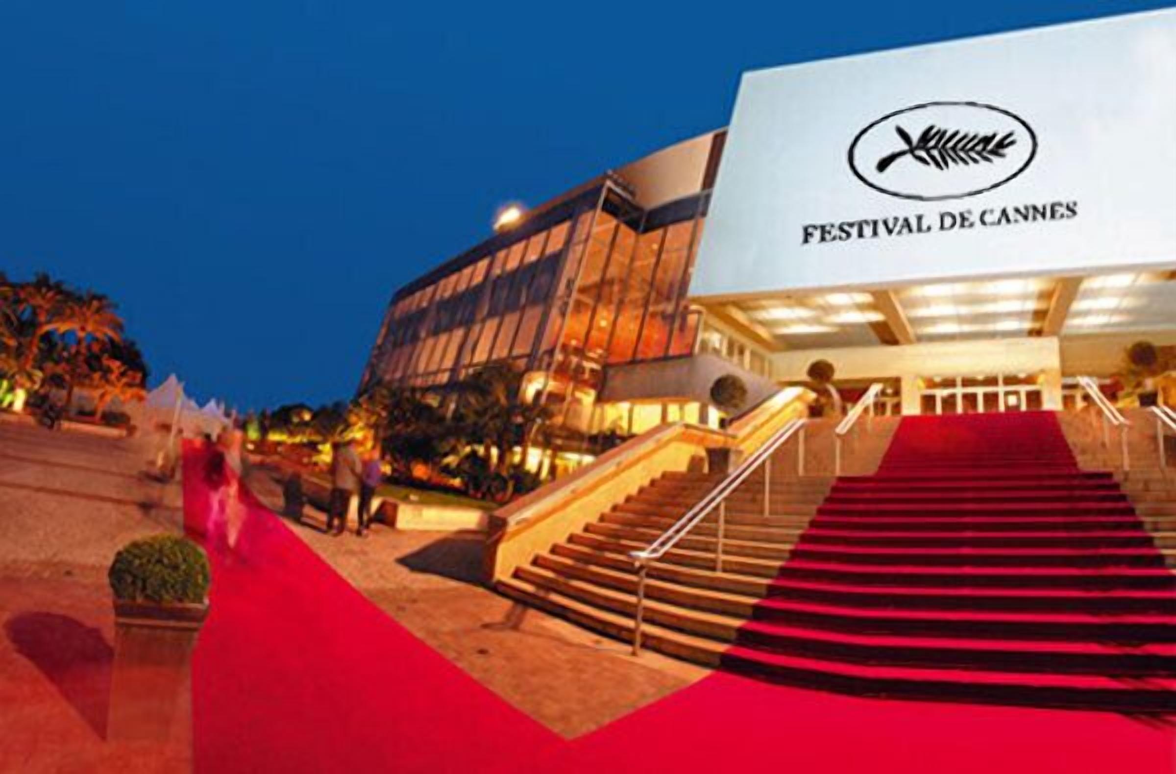 Ein Gebäude mit rotem Teppich, der zu einer Treppe führt, und die Inschrift "FESTIVAL DE CANNES" ist auf der Fassade sichtbar.