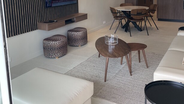 Un salon moderne avec un téléviseur à écran plat fixé au mur, une table de salle à manger ronde avec des chaises et un canapé.