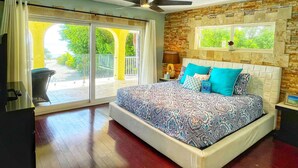 A bedroom with a bed, a ceiling fan, a window with a view of greenery, and a sliding glass door leading to an outdoor area. - ASK ABOUT Sept-Oct2026 SPECIAL! 14Bd10Bth Home Comfortably Accommodates Up to 30 (Marathon)