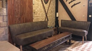 A room with two leather sofas, a wooden bench, stone walls, and mounted weapons. - Interesting holiday apartment GUARDROOM in the Leppersdorf manor (Wachau)