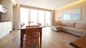 A modern living room with a wooden dining table and chairs, a beige sofa, and a large world map on the wall. - SUITE WITH VESUVIUS VIEW TERRACE IN HISTORIC CENTER (Napoli)