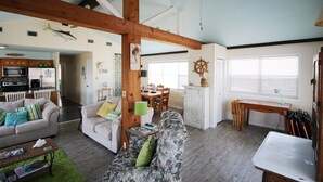 Un salón amplio con techo alto, vigas de madera, comedor y cocina.