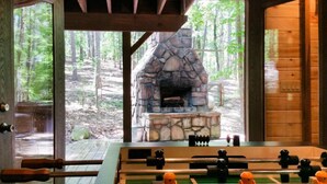 A rustic cabin with a stone fireplace, wooden deck, and a foosball table. - At Last, you can enjoy life with all the comforts of your own home on your stres (Broken Bow)