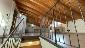 A spacious attic room with a wooden ceiling and a metal staircase. - The terrace - vacation home with lake view (San Zeno di Montagna, Verona)