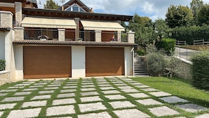 A two-story house with a covered patio and a stone-tiled driveway. - The terrace - vacation home with lake view (San Zeno di Montagna, Verona)