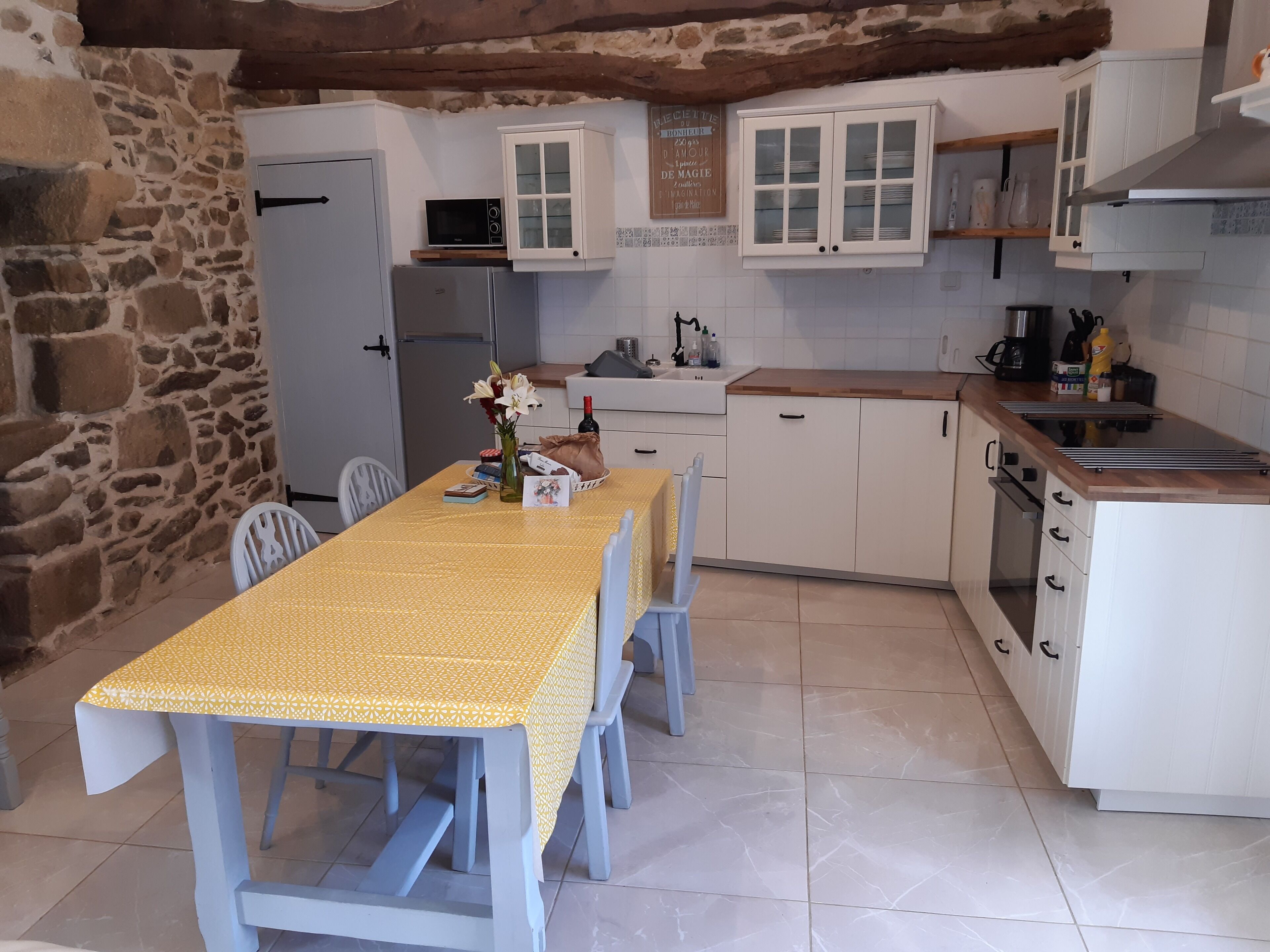 A compact kitchen with white cabinets, a built-in oven, and a dining table with chairs.