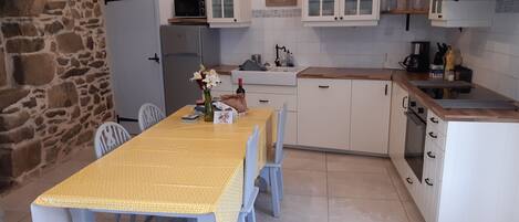 A compact kitchen with white cabinets, a built-in oven, and a dining table with chairs.