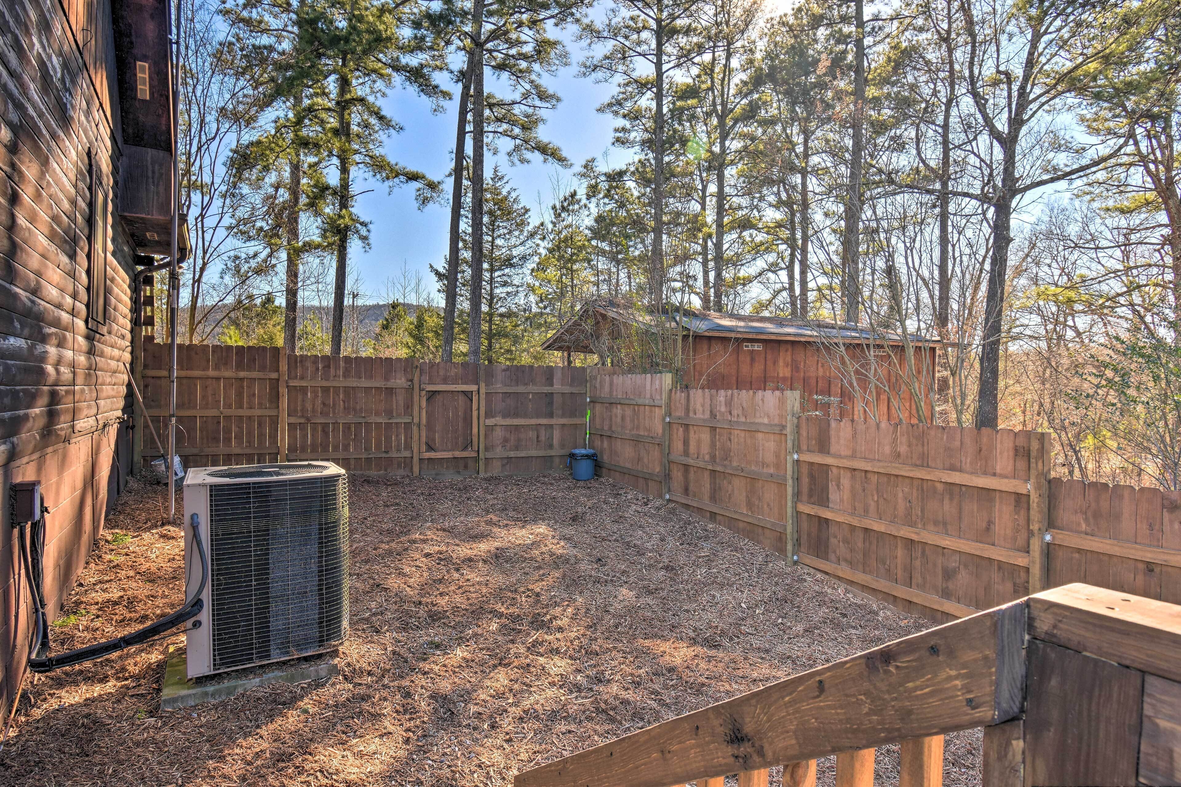 Un espacio al aire libre cercado con una estructura de madera, un equipo de aire acondicionado grande y suelo de grava.