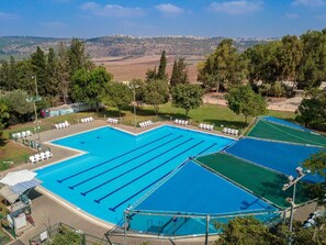 Una piscina al aire libre de temporada, sombrillas, tumbonas
