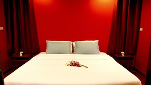 Ein Hotelzimmer mit einem großen Bett, zwei Nachttischen und roten Vorhängen.