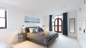 Une chambre moderne avec un grand lit, des lampes de chevet, un plateau avec des articles pour le petit-déjeuner et une vue sur l’extérieur par une fenêtre.