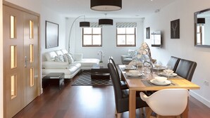 Un espace repas moderne avec une table en bois dressée pour quatre personnes, entourée de chaises noires et blanches.