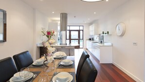 Une cuisine moderne avec des armoires blanches, une hotte de cuisinière en acier inoxydable et une horloge ronde au mur.