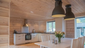 Een moderne keuken met houten lambrisering, een centraal eiland en hanglampen.