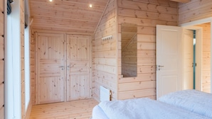 Een houten kamer met een bed, twee deuren en een klein raam.