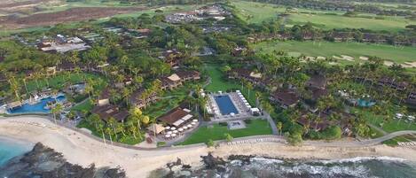 Ett flygbildsfoto av ett semesterområde med flera byggnader, en swimmingpool och en golfbana.