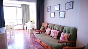 A living room with a sofa, chairs, a table, and a window with curtains. - First Line of Levante Beach (Benidorm)