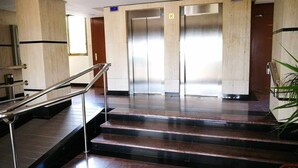 A lobby with a staircase, elevators, and a potted plant. - First Line of Levante Beach (Benidorm)