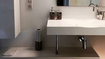 A modern bathroom with a large white sink, a mirror, and a towel rack.
