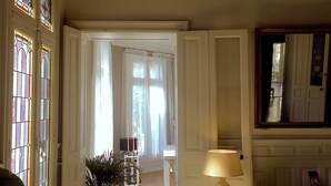 A room with a piano, a lamp, and a mirror on the wall. - Maison d'hôtes La Domitia (Montbazin)