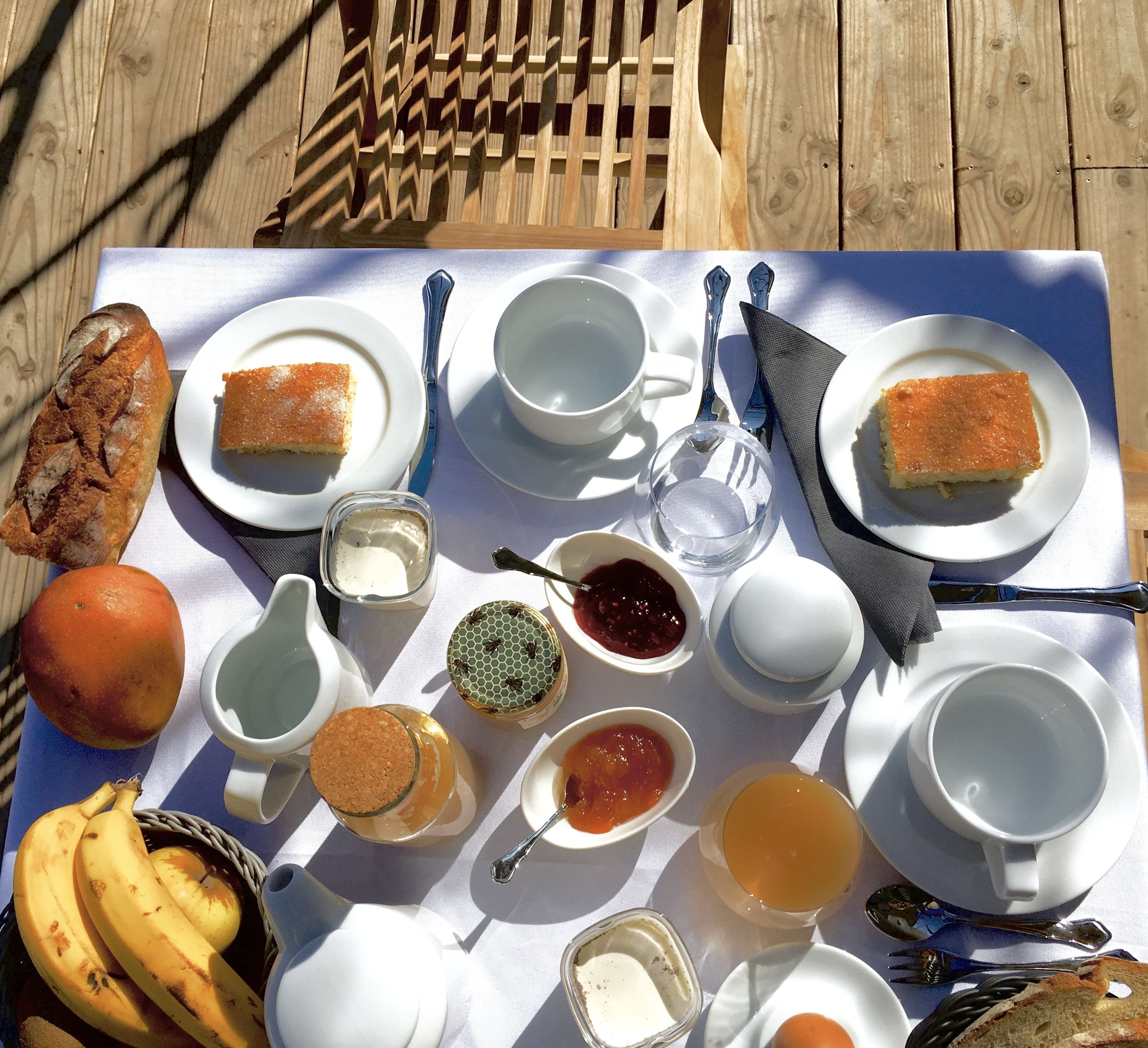A picnic setup with bread, fruits, and various condiments on a table.