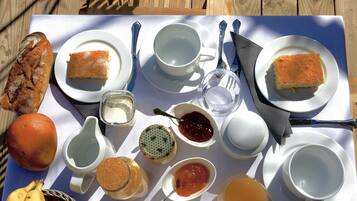 A picnic setup with bread, fruits, and various condiments on a table.