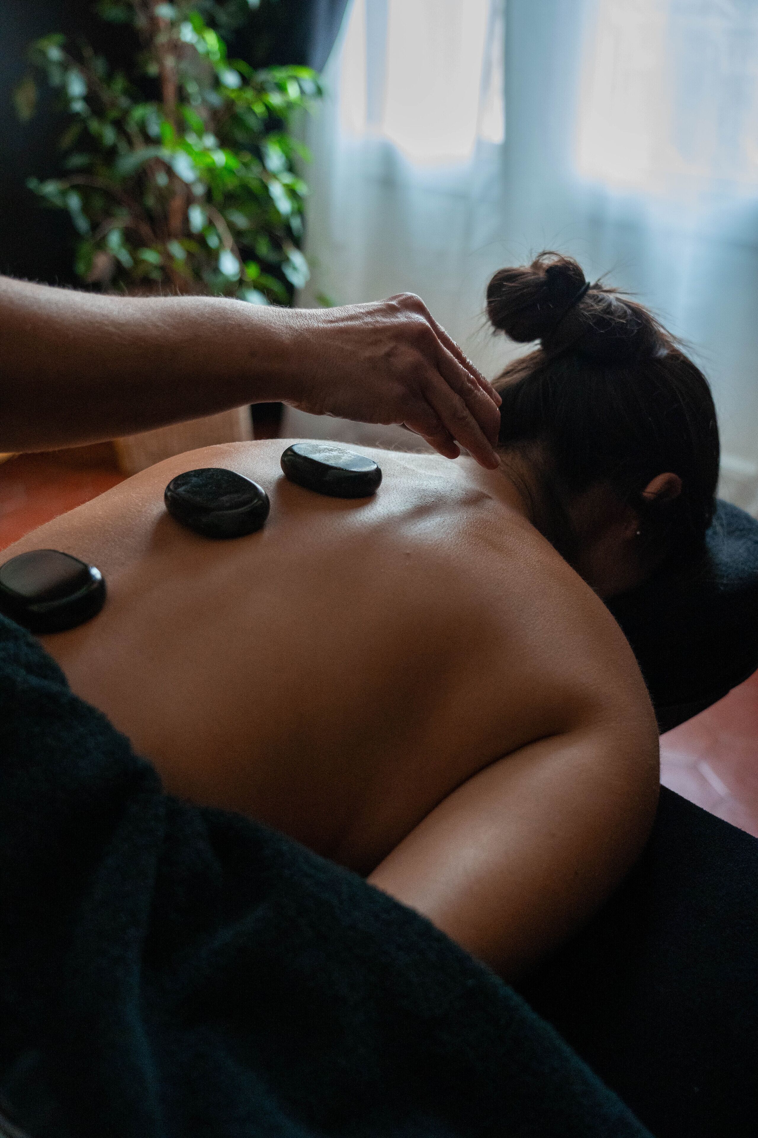 Eine Person erhält eine Rückenmassage mit warmen Steinen.