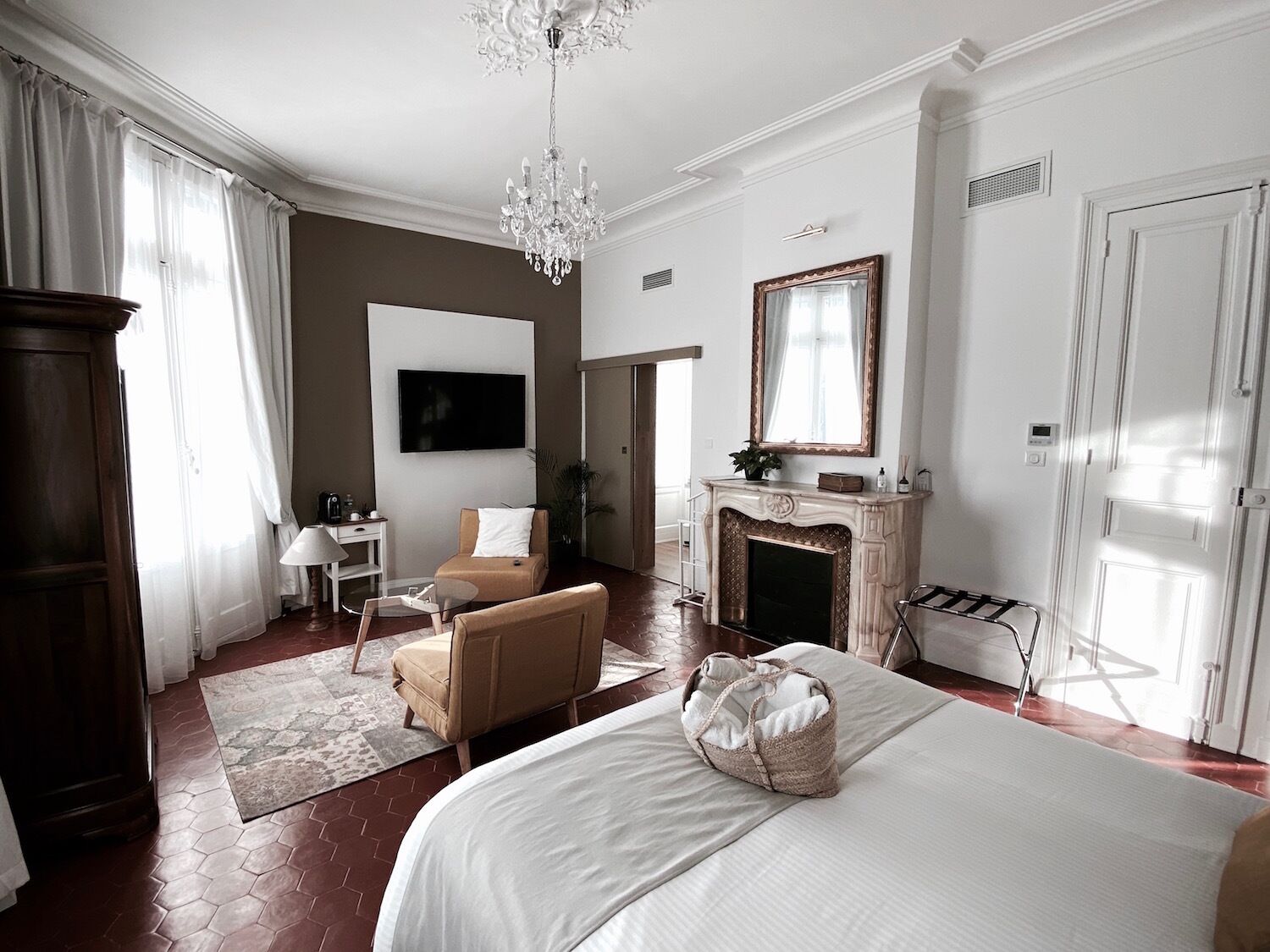 A hotel room with a large bed, a fireplace, a television, a desk, and a chair.