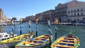 A marina with colorful boats docked, a clear sky, and historic buildings in the background. - Maison d'hôtes La Domitia (Montbazin)
