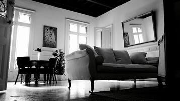 A room with a sofa, chairs, a table, and a large mirror.
