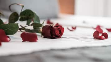 Un lit recouvert d’un drap blanc et parsemé de pétales de rose.