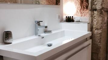 A modern bathroom with a white sink, a mirror, and a towel rack.