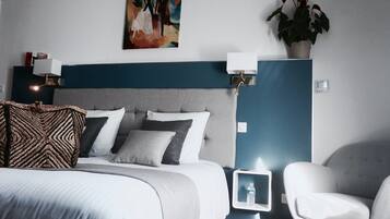 Una habitación de hotel moderna con una cama grande, un cabecero, mesitas de noche con lámparas, una botella de agua y una planta en maceta.