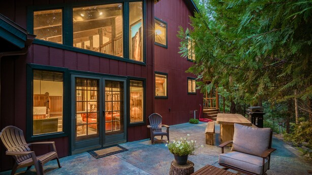 A two-story building with large windows, outdoor seating, and a wooden deck.