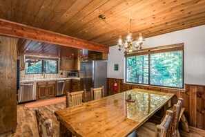 A spacious kitchen with wooden cabinetry, stainless steel appliances, and a large island with chairs. - Johnson's Firefall Lodge - 2 miles from Yosemite National Park! (Fish Camp)