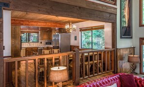 A rustic cabin interior with a kitchen, dining area, and a large window offering a forest view. - Johnson's Firefall Lodge - 2 miles from Yosemite National Park! (Fish Camp)