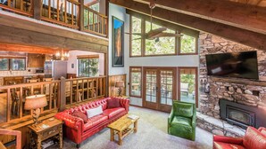 A spacious living area with a red leather sofa, a green chair, and a stone fireplace.