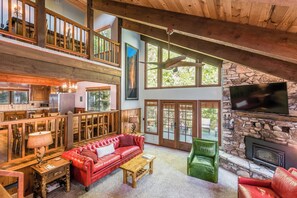 A spacious living area with a red leather sofa, a green chair, and a stone fireplace. - Johnson's Firefall Lodge - 2 miles from Yosemite National Park! (Fish Camp)