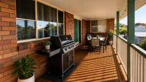 A covered patio with a grill, outdoor seating, and a view of the neighborhood.