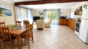A spacious kitchen with a dining area, a TV, and a view of the outdoors.