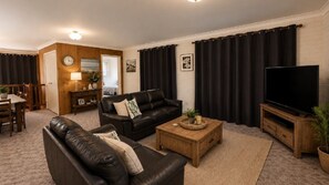 Una sala de estar con sofá, mesa de centro, televisión y un comedor con mesa y sillas.