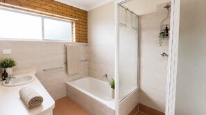 A bathroom with a bathtub, a shower, a sink, and a window. - 'Seaduced by Minnie, TOP NOTCH (MINNIE WATER)