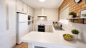 Una cucina moderna con mobili bianchi, forno integrato e lavello in acciaio inossidabile.