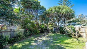A backyard with a wooden fence, various trees, and a grassy area.