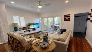 A living room with a television, sofa, chairs, a coffee table, and a sign warning of rocks. - Sea Legs - Gorgeous Beachfront (WOOLI)