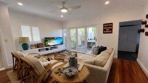 A living room with a television, sofa, chairs, a coffee table, and a sign warning of rocks.