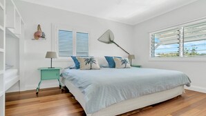 A bedroom with a bed, two nightstands, a hanging lamp, and a window with blinds. - Sea Legs - Gorgeous Beachfront (WOOLI)